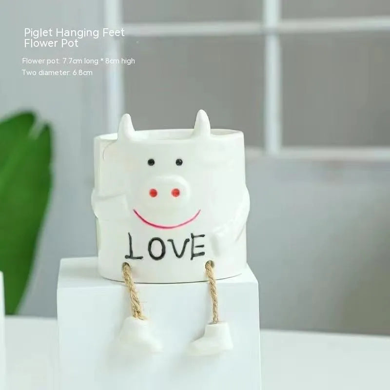 Ceramic cartoon-style succulent flowerpot with hanging foot design on desktop