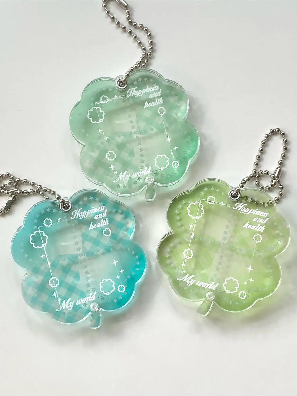 Acrylic four-leaf clover charm on a keychain for mobile phone decoration, shown in blue, green, and mint colour options.