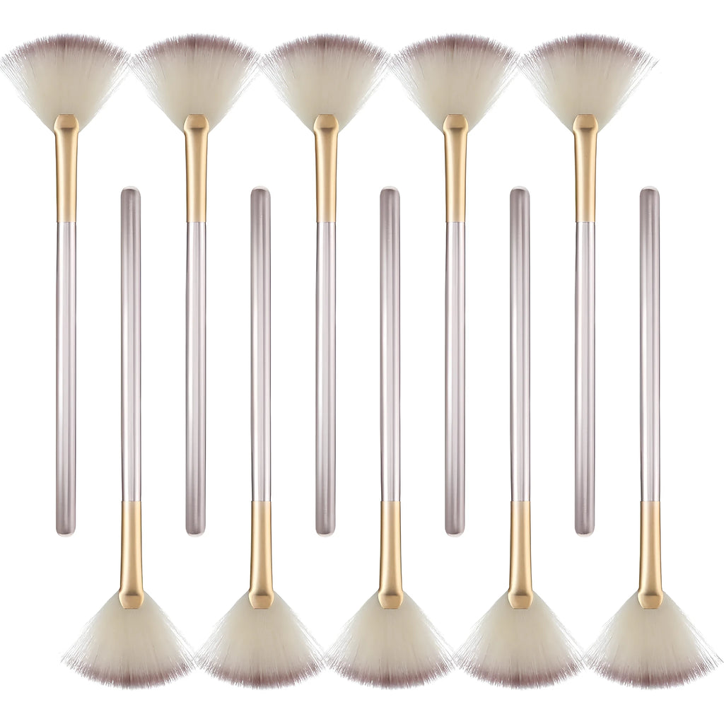 Set of 10 professional facial fan brushes with champagne finish and acrylic handles on a table.