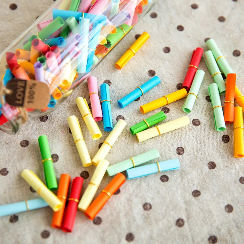 Assorted colourful mini paper scrolls with central metal eyelets for drift bottle messages.