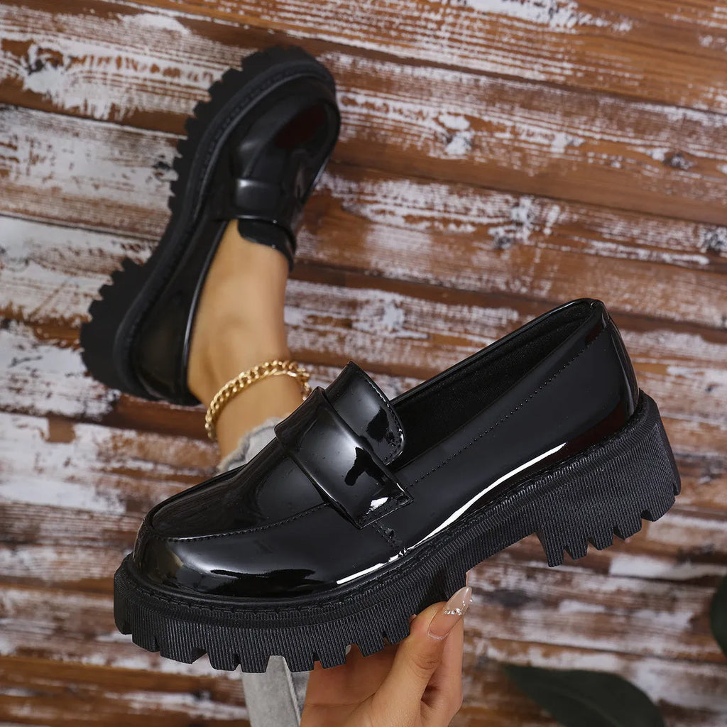 Women's black chunky heel slip-on loafers with a platform sole, shown on a foot.