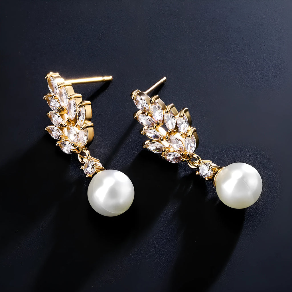 Geometric flower shaped earrings with micro inlaid zircon stones and pearl accents on a gold plated background.
