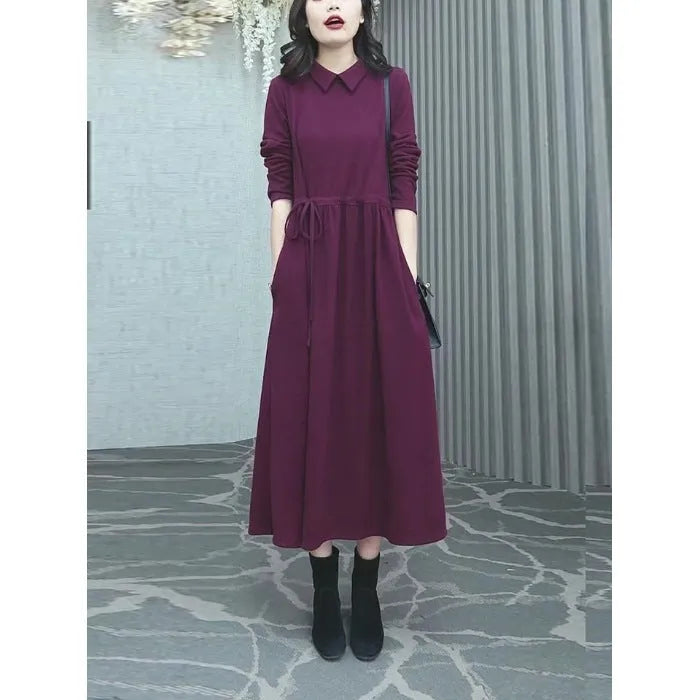 A purplish red plus size long sleeve dress with a long skirt, shown on a model.