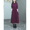 A purplish red plus size long sleeve dress with a long skirt, shown on a model.
