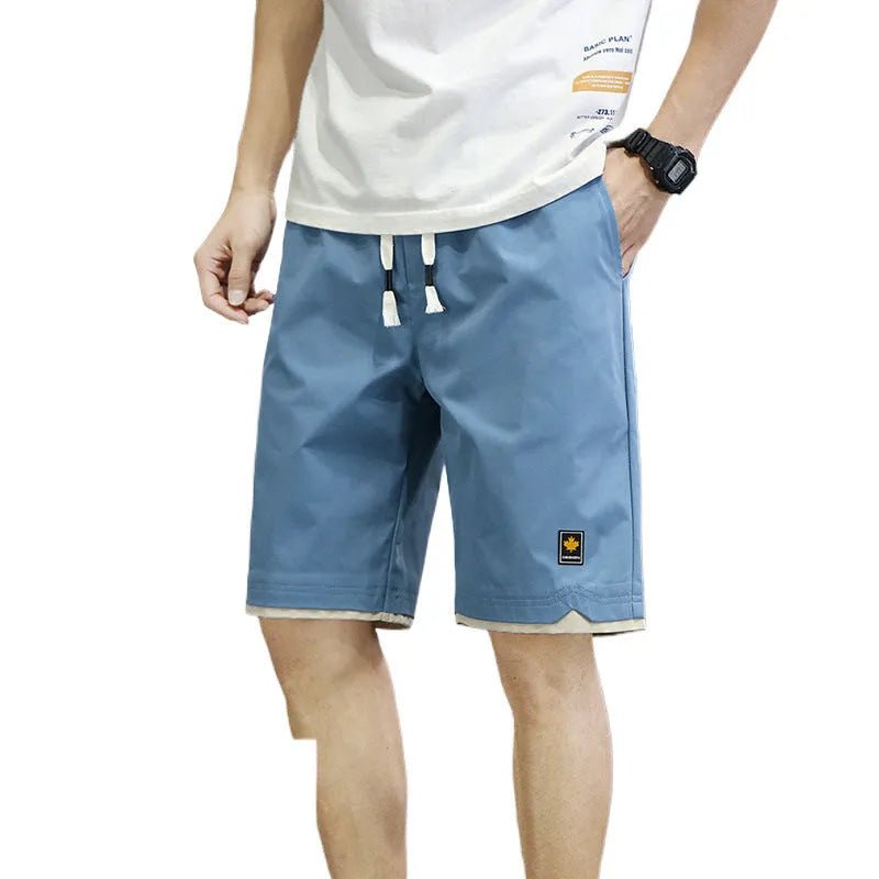 Man wearing loose straight-leg casual shorts in a solid colour on a beach.
