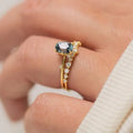 Gold-plated floral ring with a green zircon stone, shown on a finger.