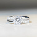 Geometric cross-design silver ring with a 1 karat moissanite stone in a four-claw setting.