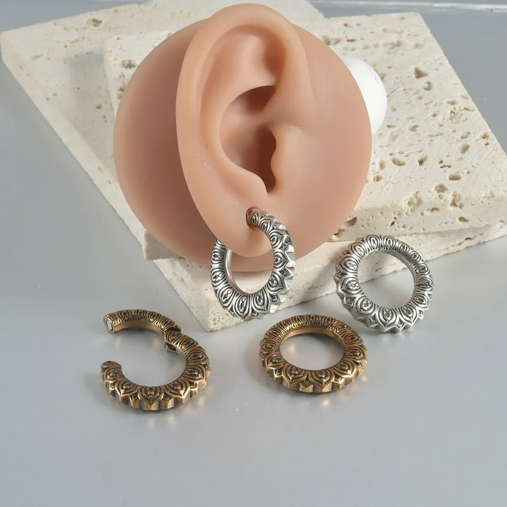 A pair of large, geometric dragon-shaped hollow out earrings in an antique silver colour.