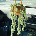 Green and white knitted car plant decoration with hanging rope on car dashboard