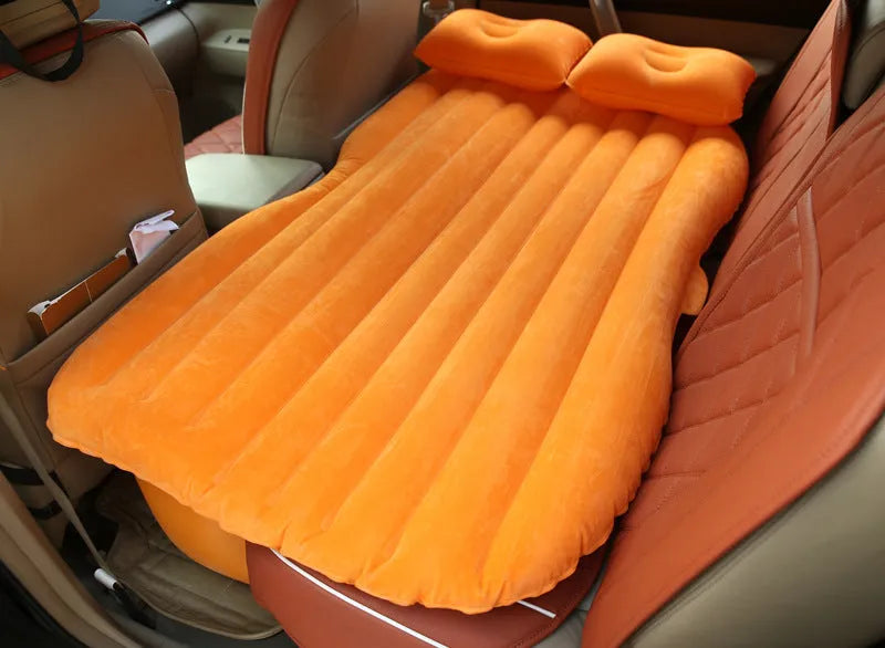 Black inflatable car bed with flocking material and two pillows, shown inside a car.