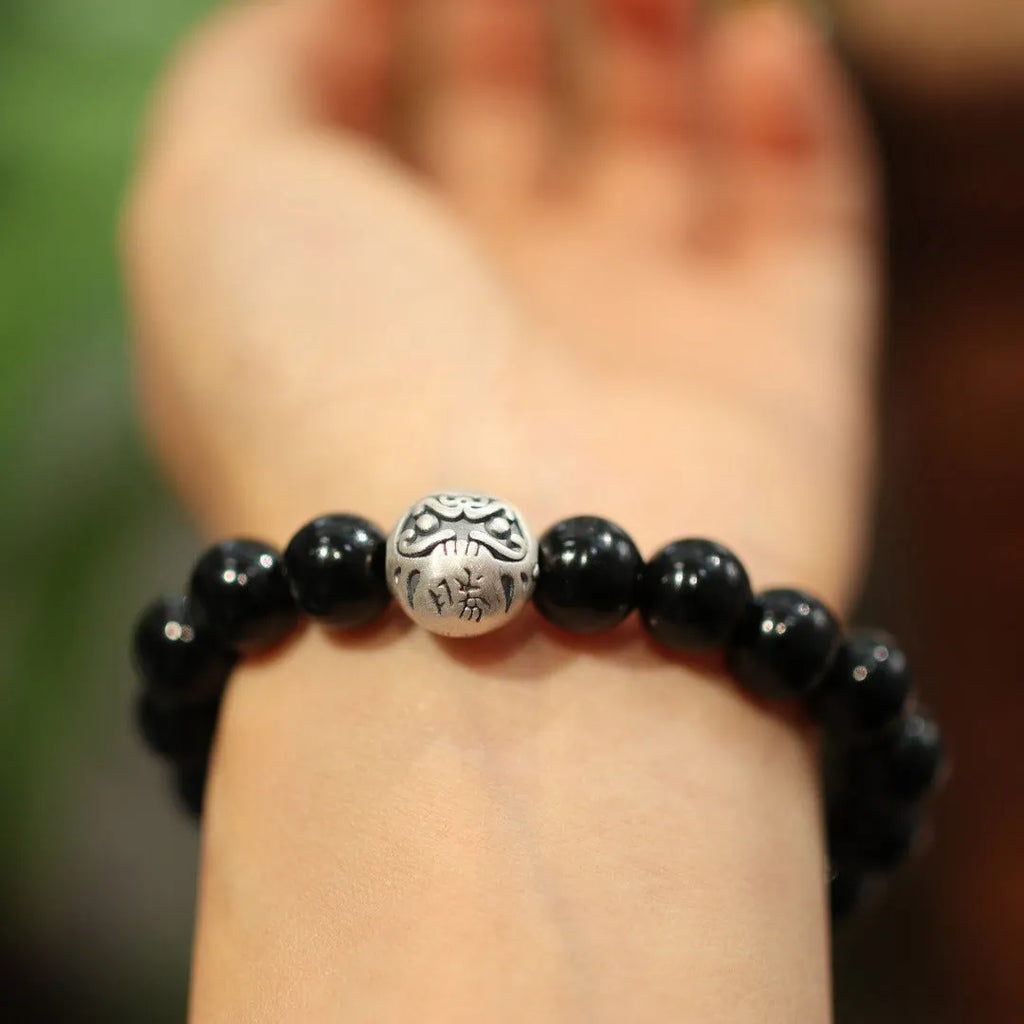 Close-up of a black agate bead bracelet with a sterling silver clasp on a wrist.