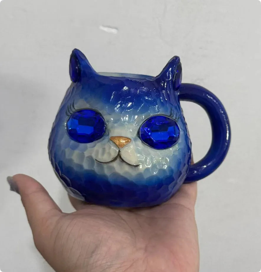 Small resin cat cup figurine in purple, green, blue, or pink colour on a shelf.