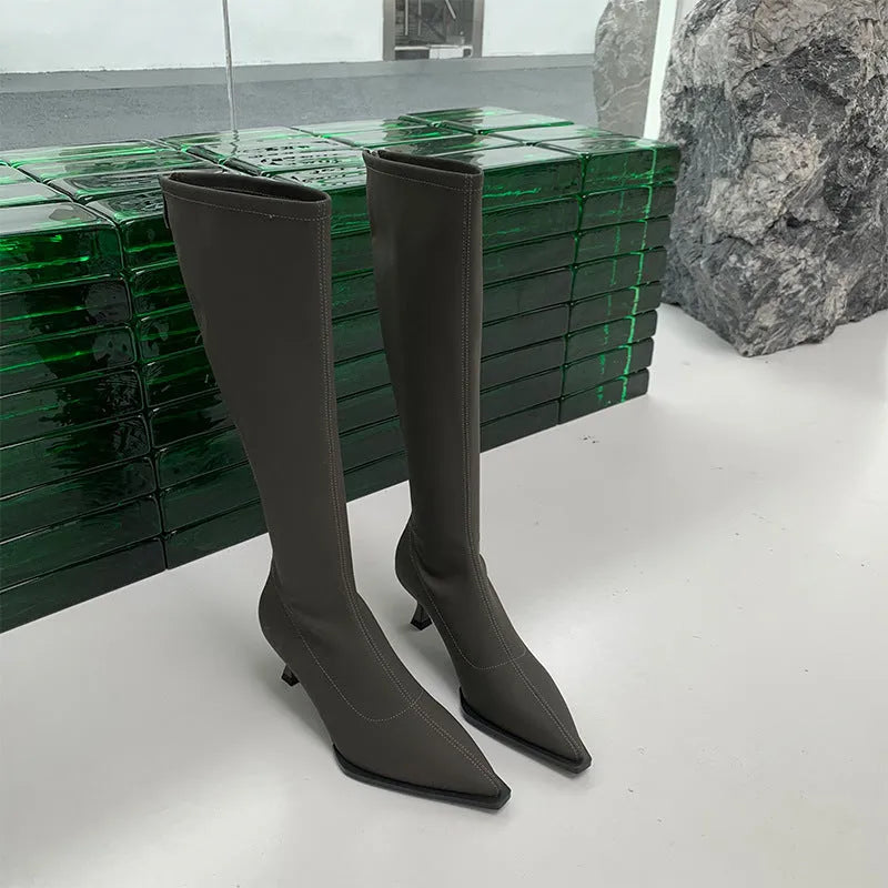 Black women's pointed toe below-the-knee boots with a stiletto heel and a back zipper closure on the side.