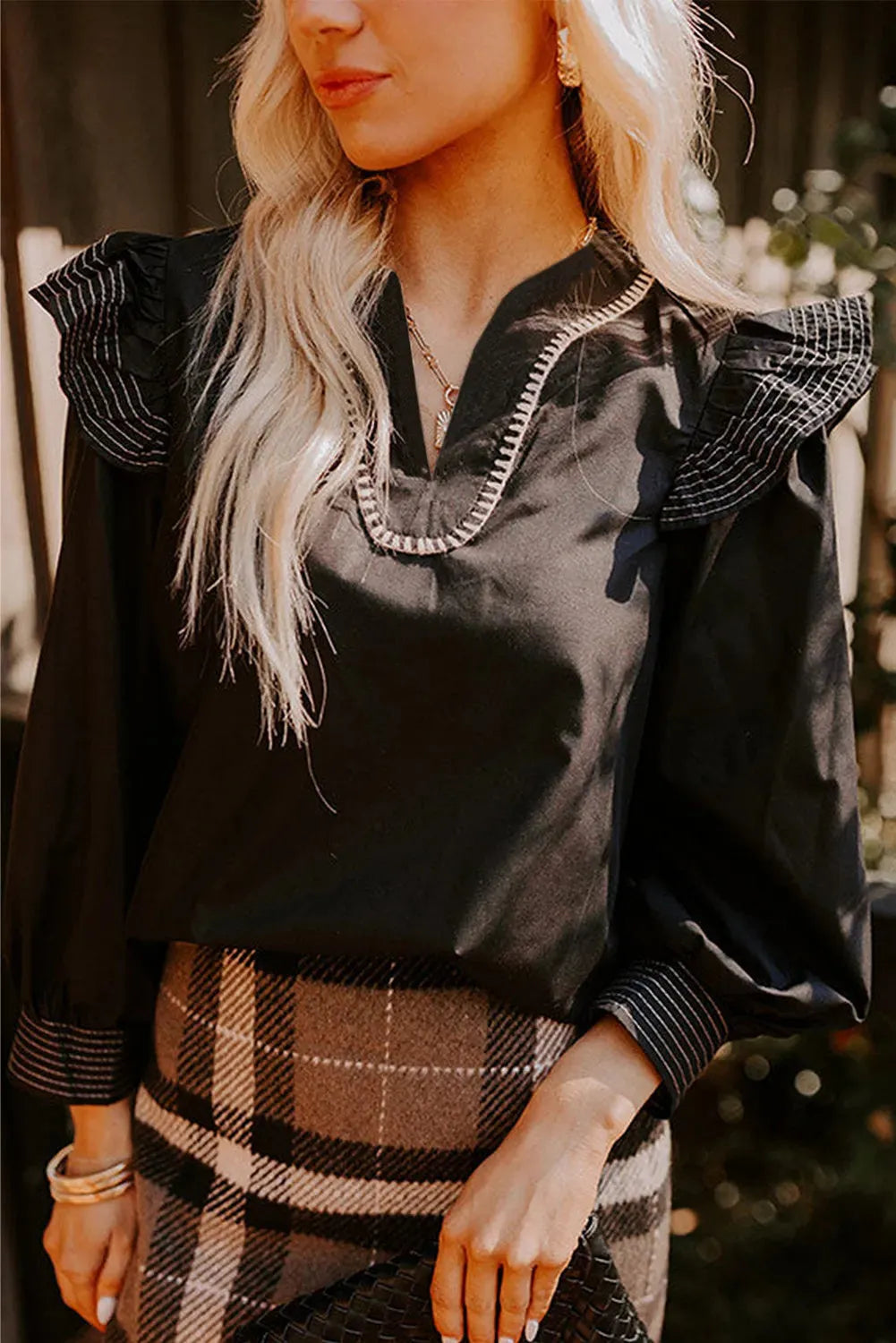 Black long sleeve blouse with V-neck and ruffle detailing on the sleeves.