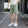 Man wearing loose straight-leg casual shorts in a solid colour on a beach.