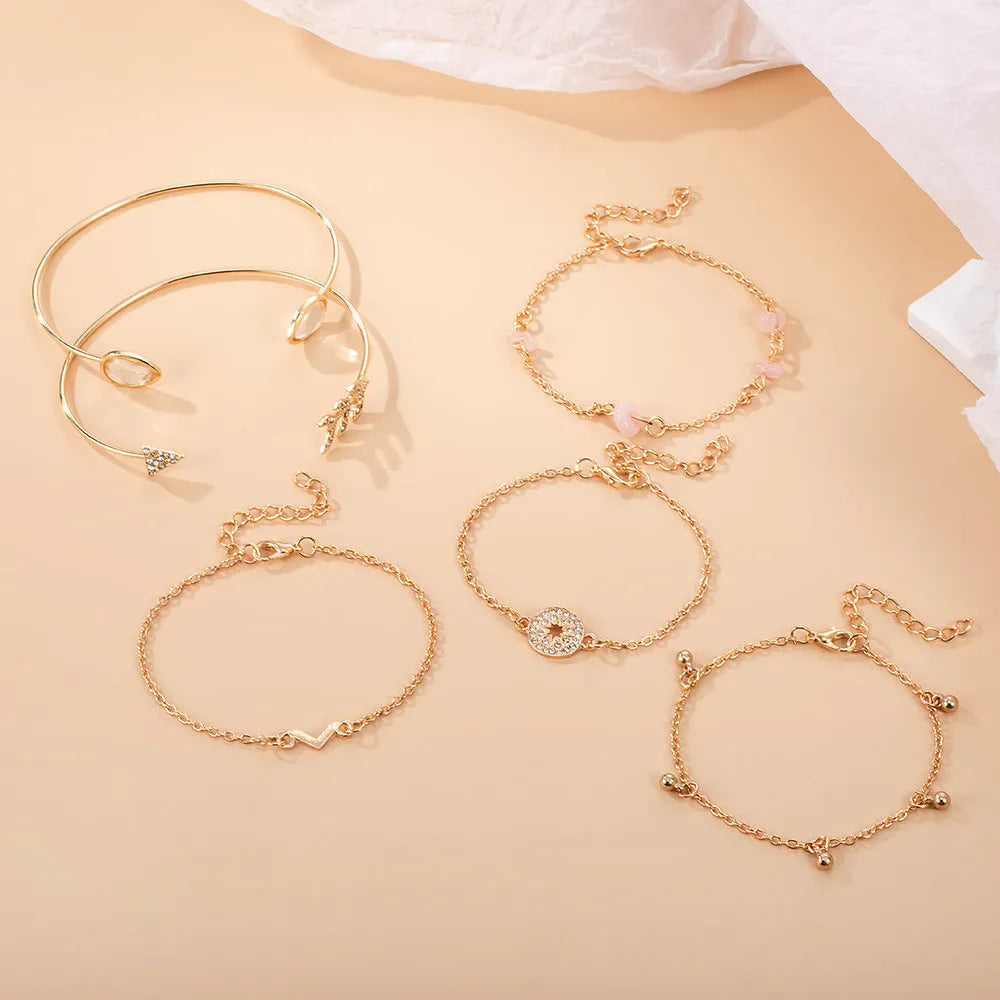 Gold zinc alloy bracelet set with six charms including spot drill, arrow, and water drop shapes.