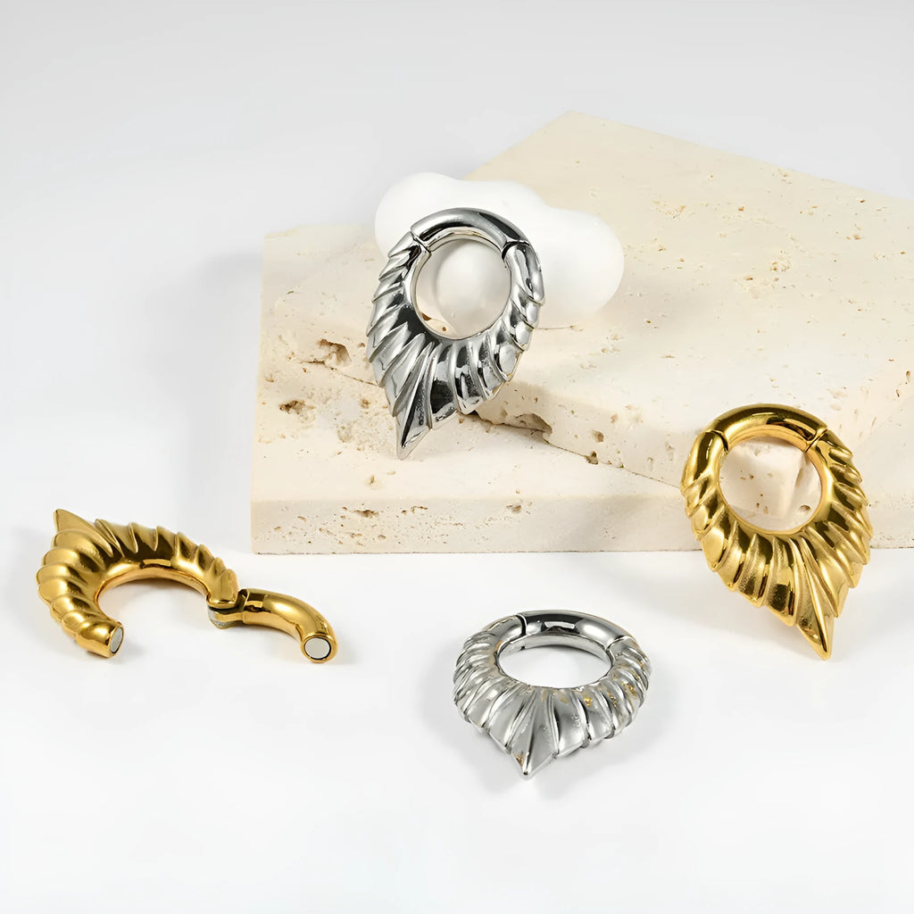 Stainless steel drop-shaped ear extender with totem design on a grey background.