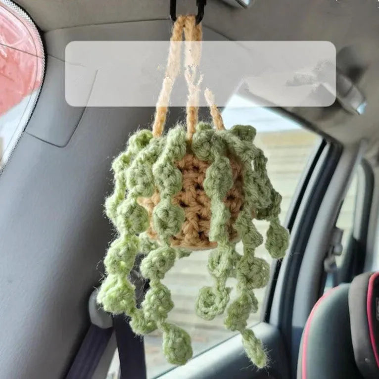 Green and white knitted car plant decoration with hanging rope on car dashboard