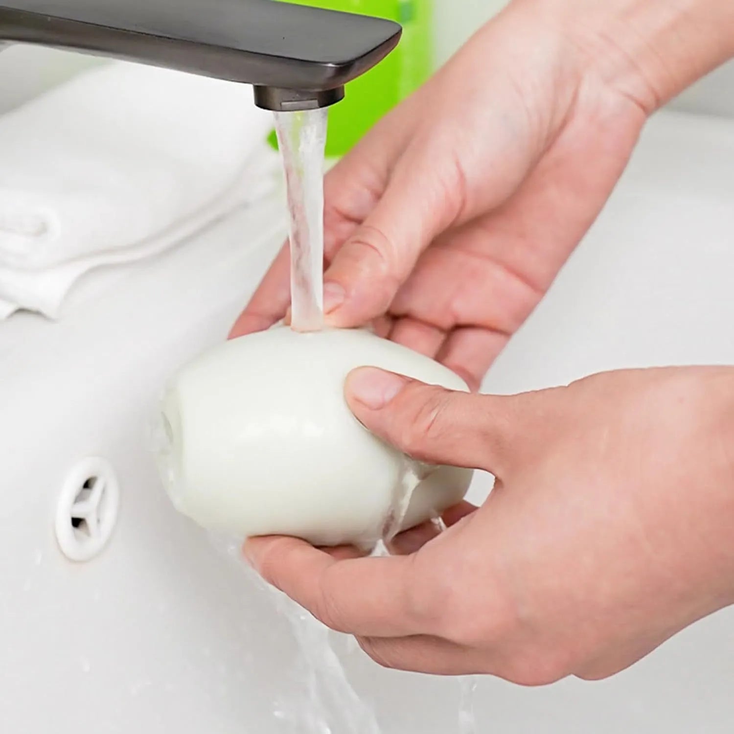 Green and white reusable gel lint roller ball for pet hair removal on fabric.