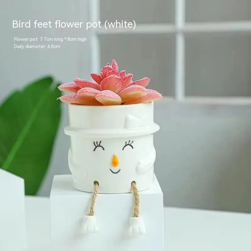 Ceramic cartoon-style succulent flowerpot with hanging foot design on desktop