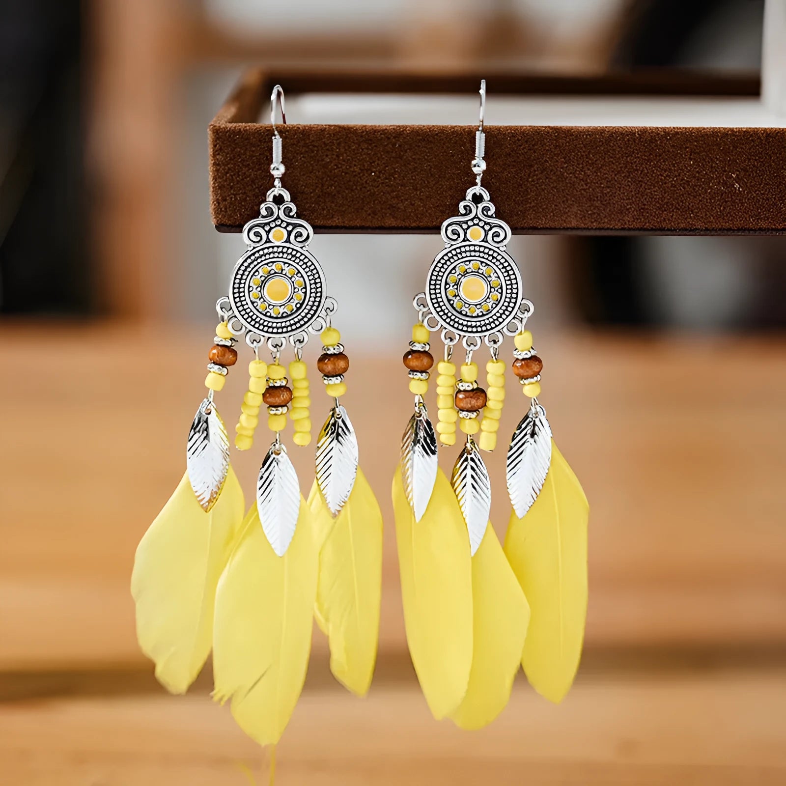Close-up of a pair of bohemian-style feather-shaped earrings with a leaf pattern, in an alloy electroplated finish.