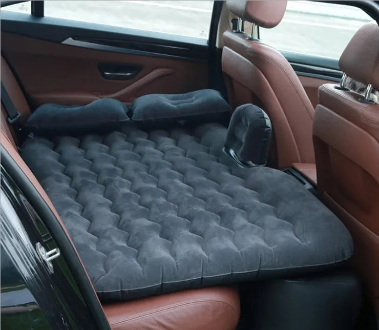 Black inflatable car bed with flocking material and two pillows, shown inside a car.