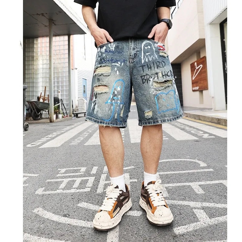 Blue mens denim shorts with ripped knees and graffiti design, straight leg fit.