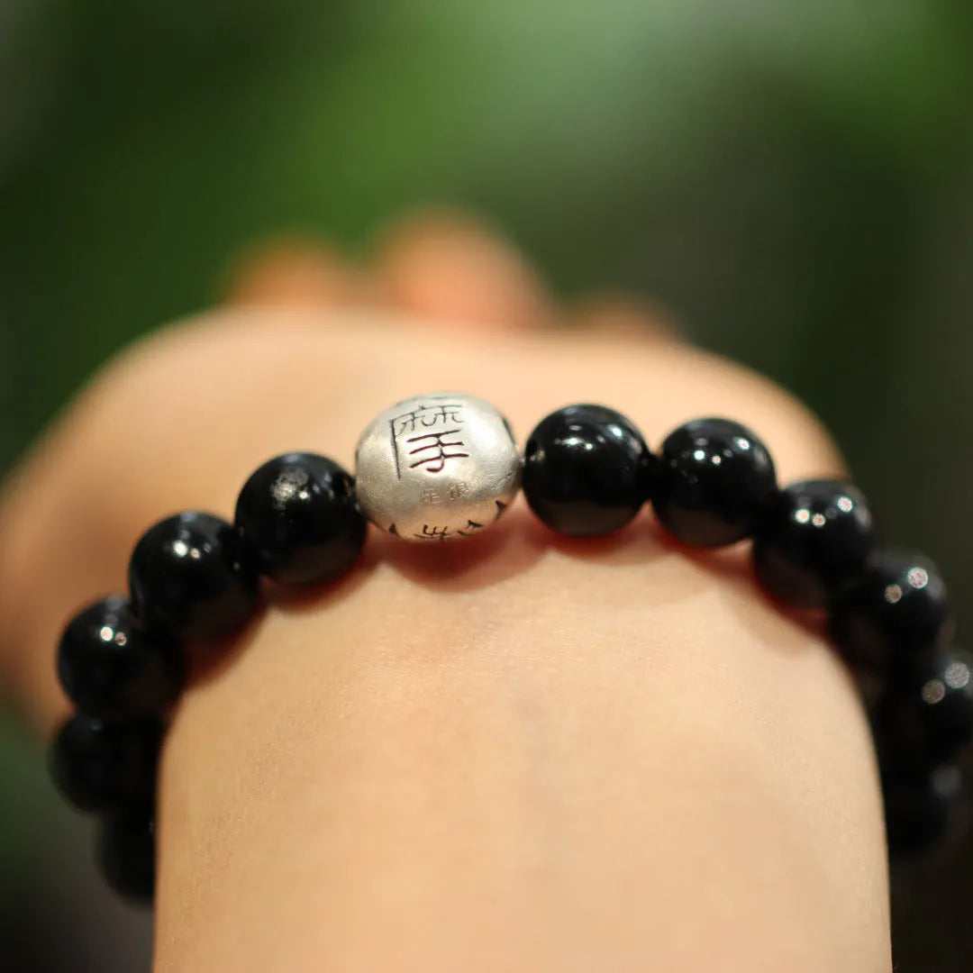 Close-up of a black agate bead bracelet with a sterling silver clasp on a wrist.