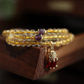 Brazil gold rutilated quartz bracelet with three gold circles in a Chinese style, hanging from chopsticks.