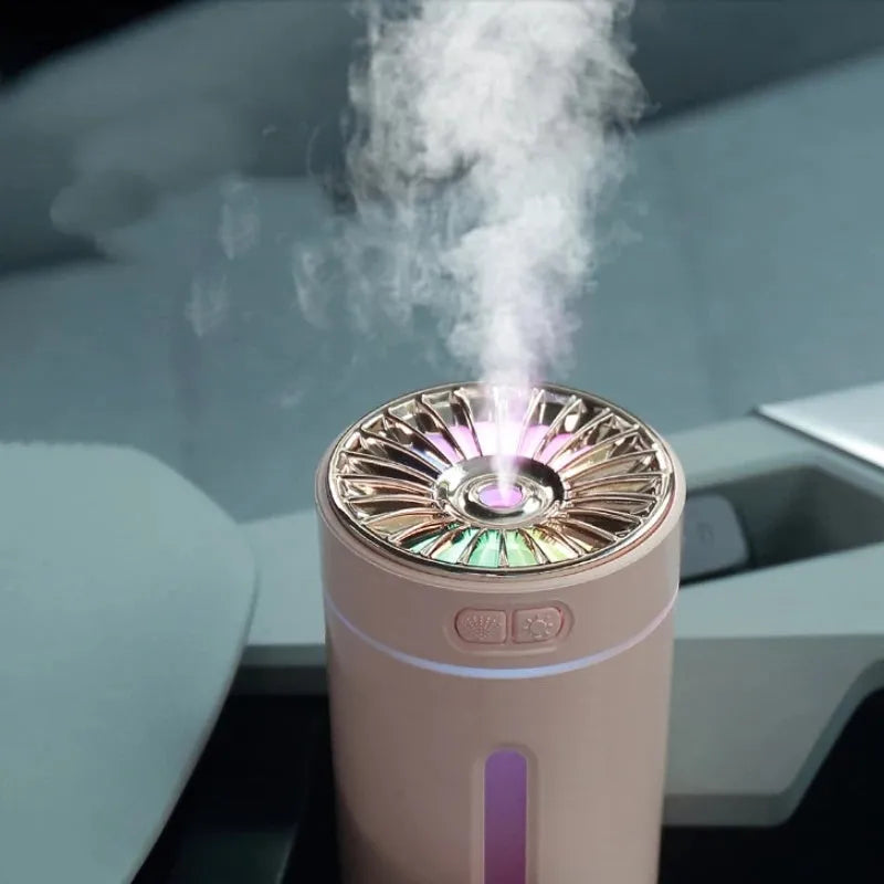 Black portable USB rechargeable car humidifier with colourful lights on a desk next to a cup