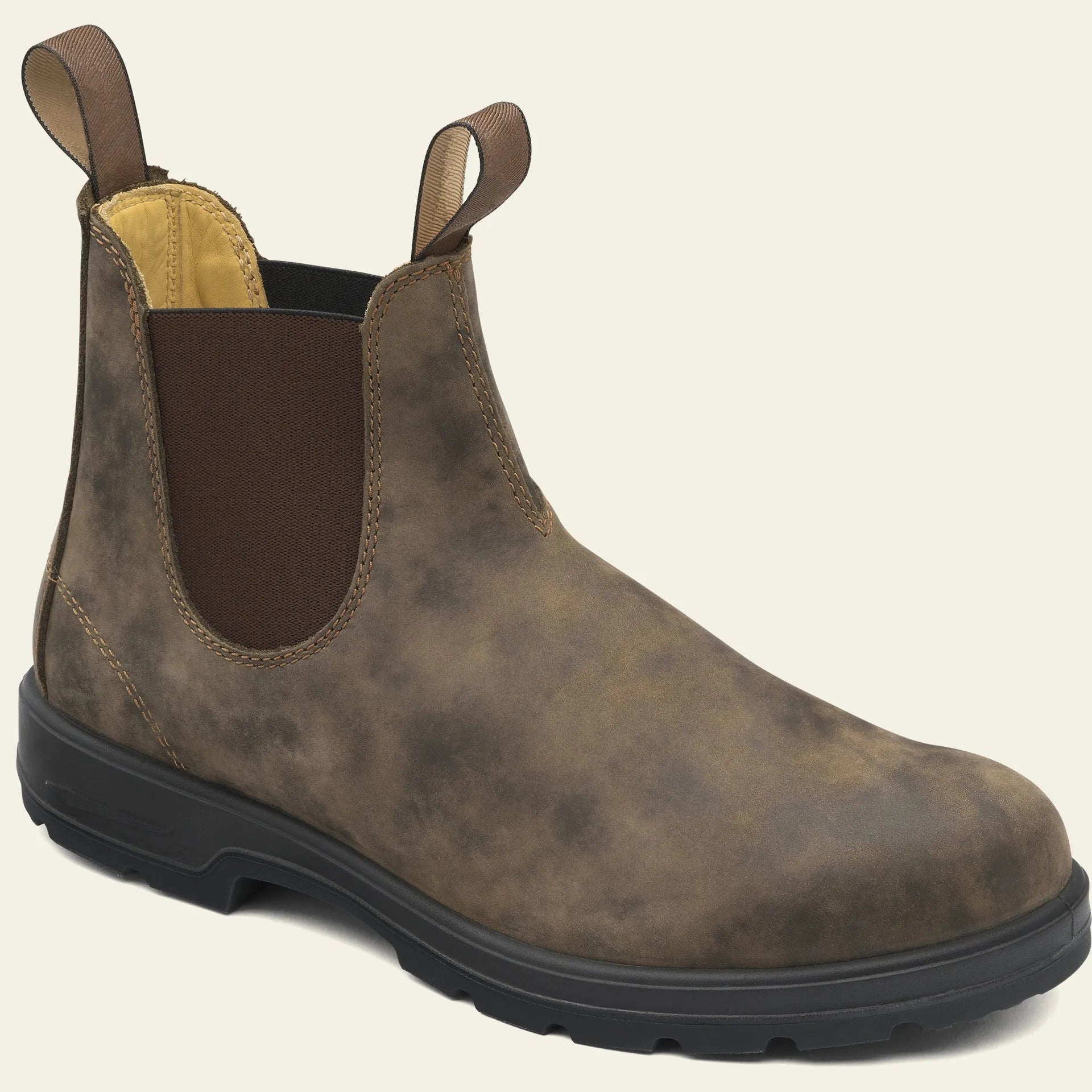 Vintage brown unisex Chelsea ankle boots with car suture stitching and a low heel on a wooden floor.