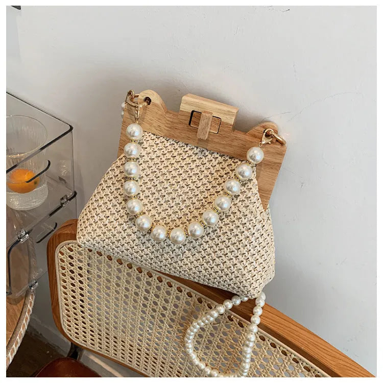 Women's soft straw woven horizontal square shoulder bag with pearl chain strap in beige colour.
