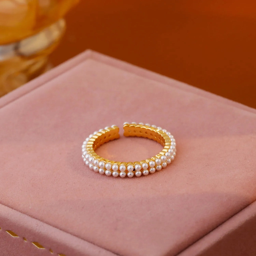 Gold coloured women's ring with open mouth design and round pearl elements on copper electroplated construction
