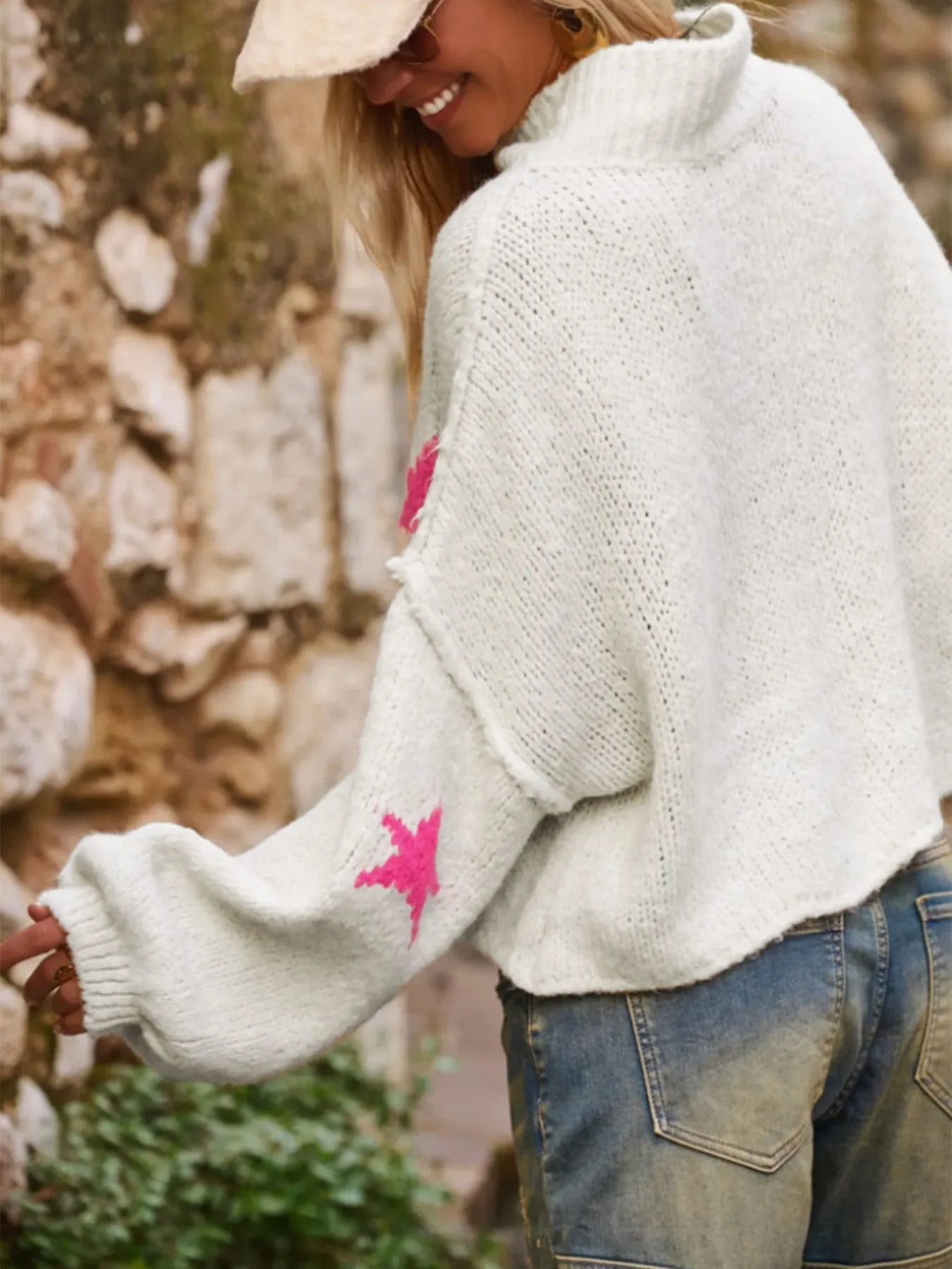 White women's loose turtleneck pullover sweater with a black five-pointed star pattern on the front.