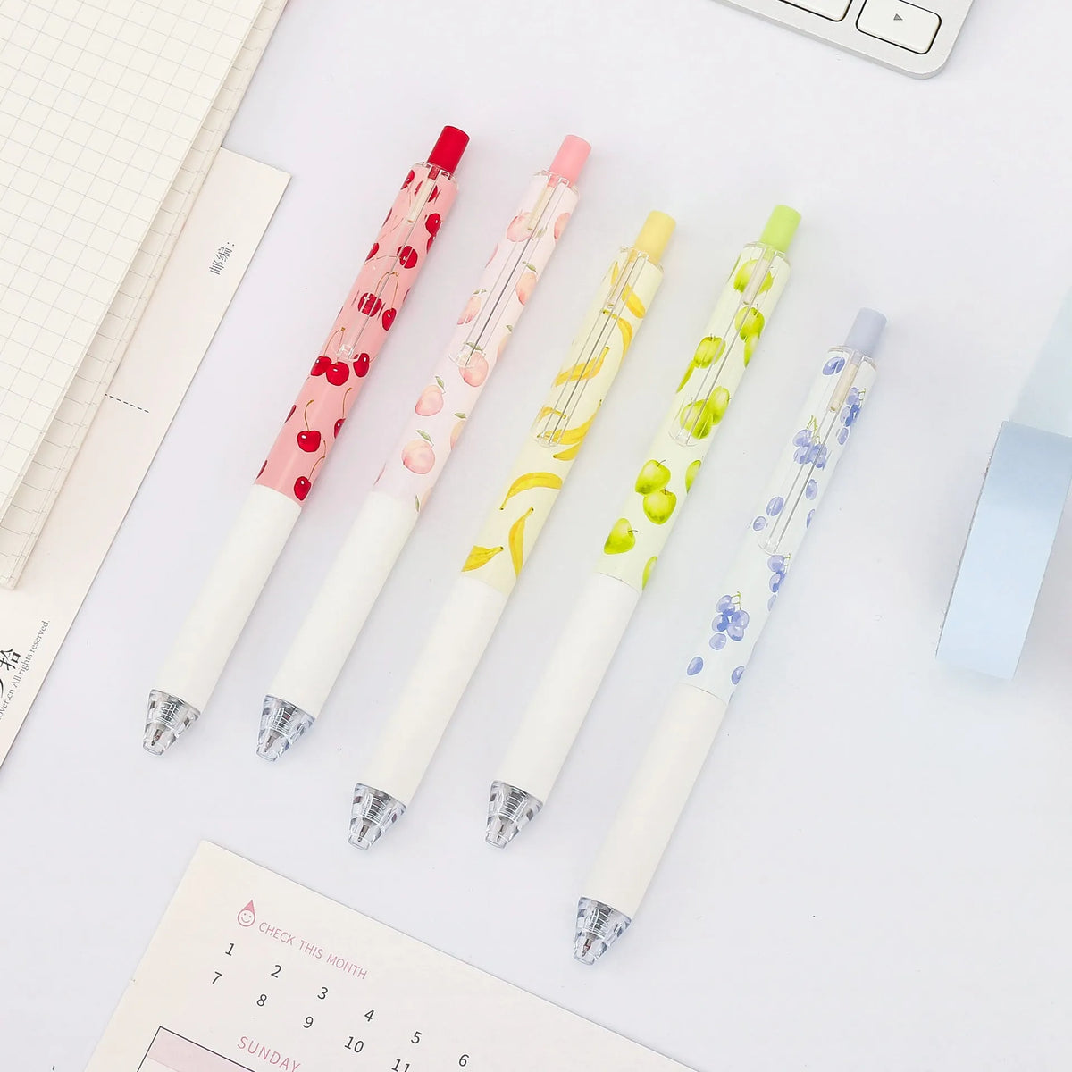 Three fruit-themed scented pressurised pens with 0.5mm black ink refills on writing surface