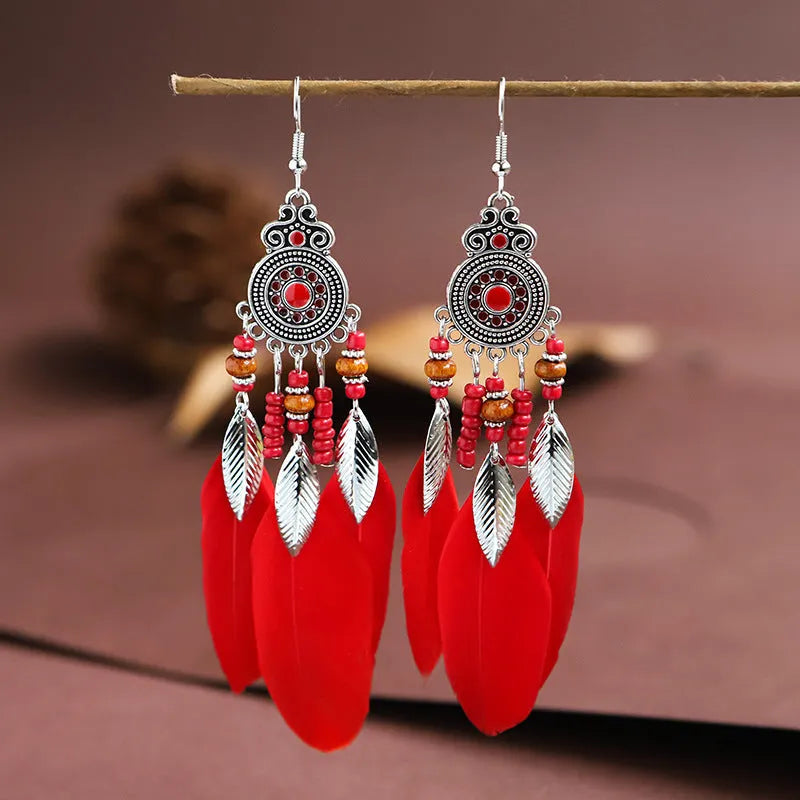 Close-up of a pair of bohemian-style feather-shaped earrings with a leaf pattern, in an alloy electroplated finish.