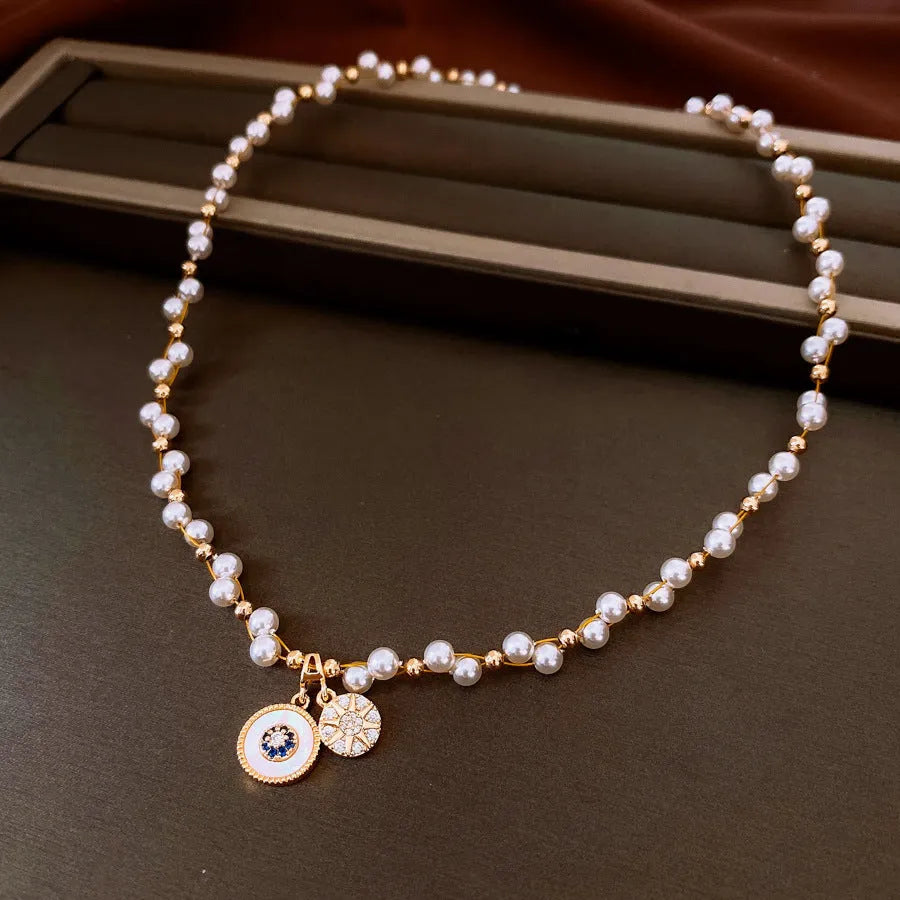 Gold electroplated zircon and imitation pearl round pendant on an adjustable clavicle chain necklace.