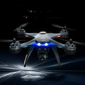 GPS remote control quadrocopter drone with camera on landing gear, next to its handle-style transmitter.