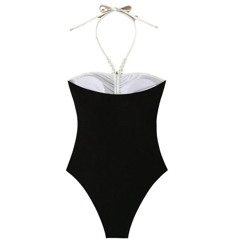 Black and white women's one-piece swimsuit with pearl spaghetti straps and a slimming cut.