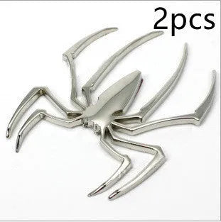 Three-dimensional zinc alloy spider bumper sticker in metallic colours on a surface.