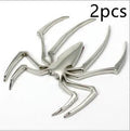 Three-dimensional zinc alloy spider bumper sticker in metallic colours on a surface.
