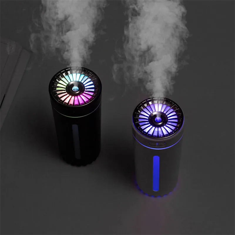 Black portable USB rechargeable car humidifier with colourful lights on a desk next to a cup