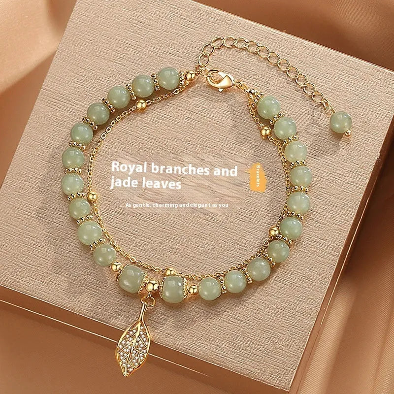 A Chinese style glass bracelet with bamboo leaf and bead designs on a wrist.