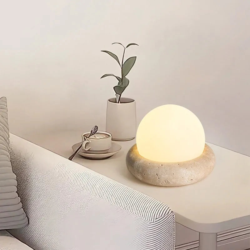 Modern cream-coloured bedside table lamp with wireless remote control on a nightstand.