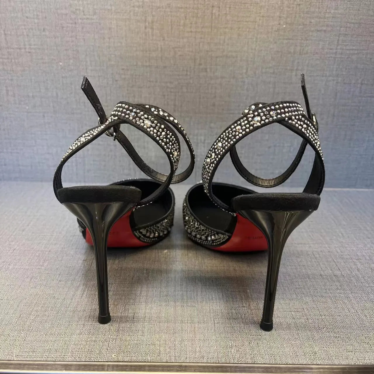Women's black high heel shoe with stiletto heel, pointed toe, shallow cut, and red sole.