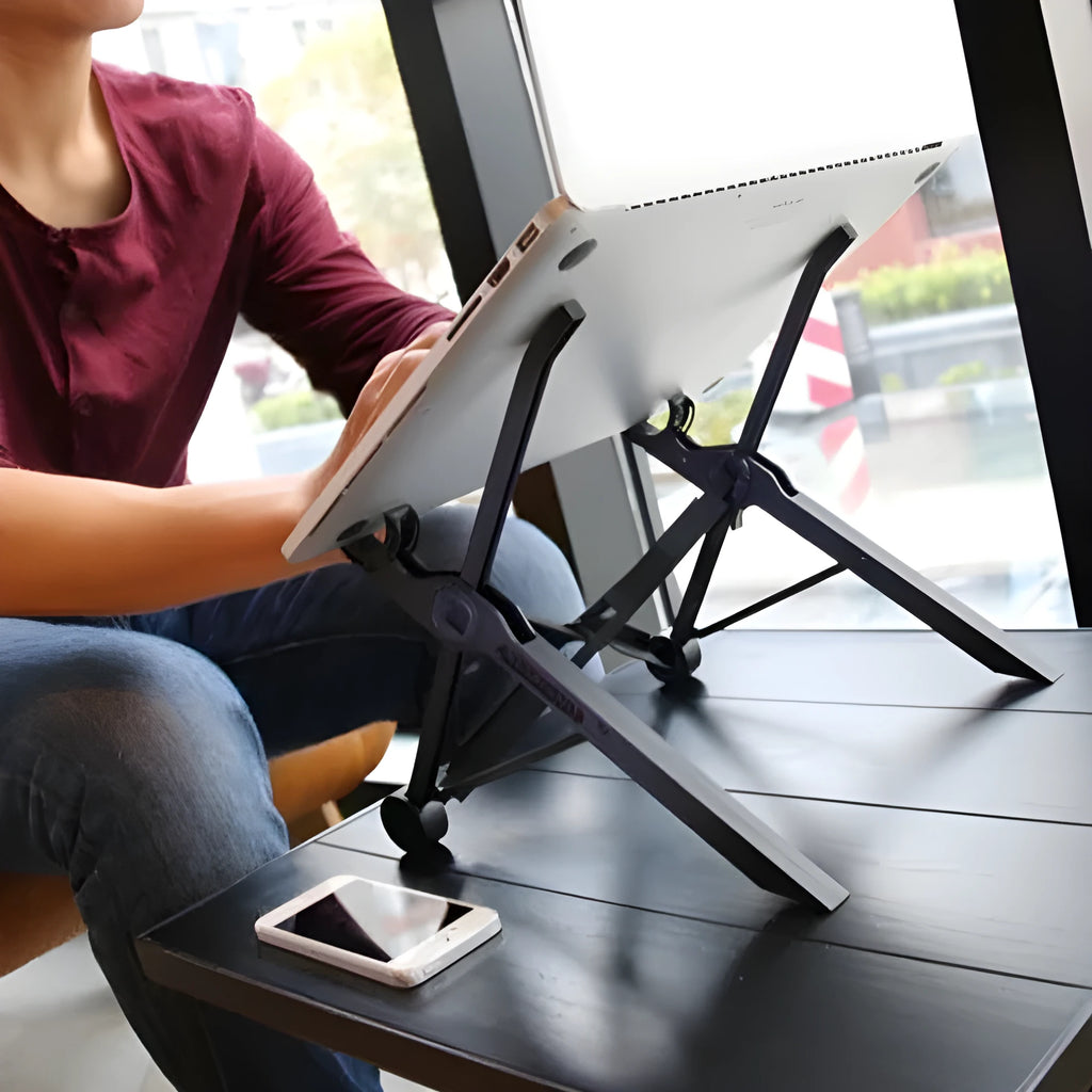 Sagacious black portable folding laptop stand on a wooden desk next to a laptop.