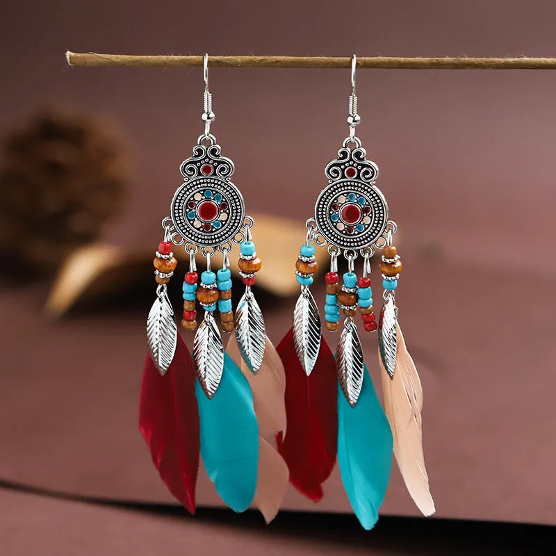 Close-up of a pair of bohemian-style feather-shaped earrings with a leaf pattern, in an alloy electroplated finish.