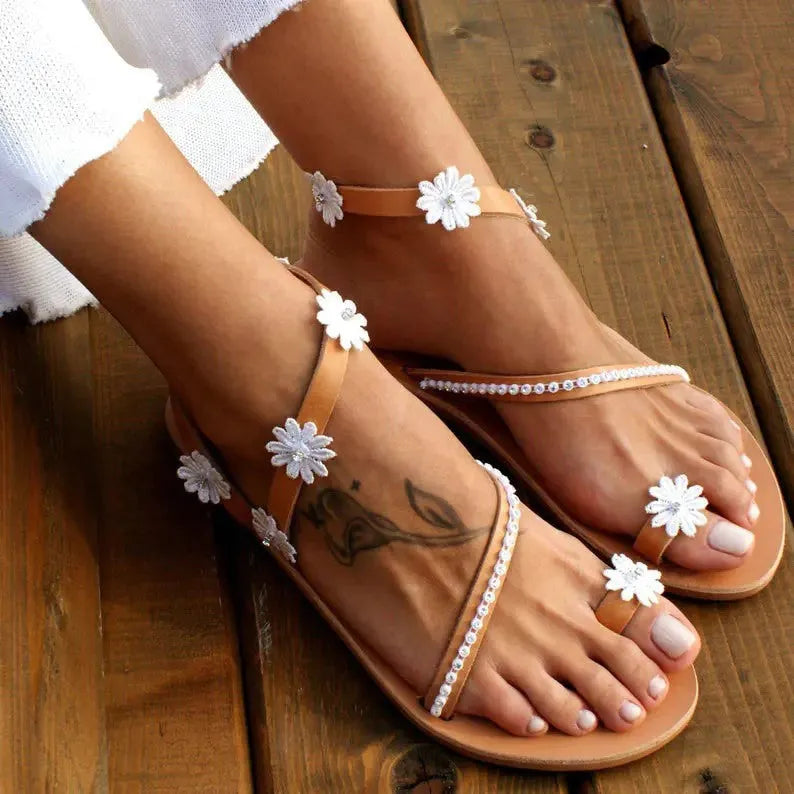 Brown Roman sandals with floral pattern, flat rubber sole, and herringbone toe design