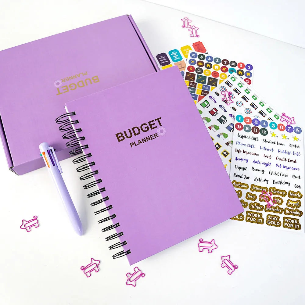 Purple coil-bound A5 financial planning notebook with pen, stickers, and paper clips for monthly budgeting