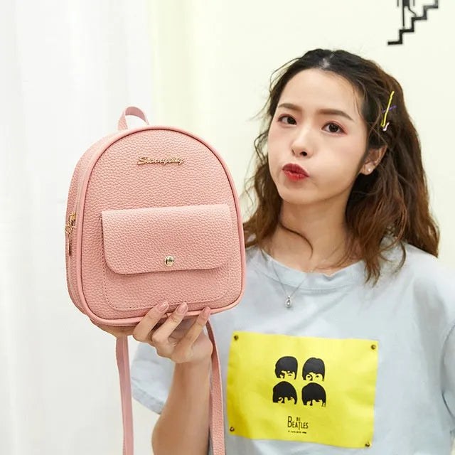 Small black PU women's backpack with zipper, shown alongside a mobile phone for scale.